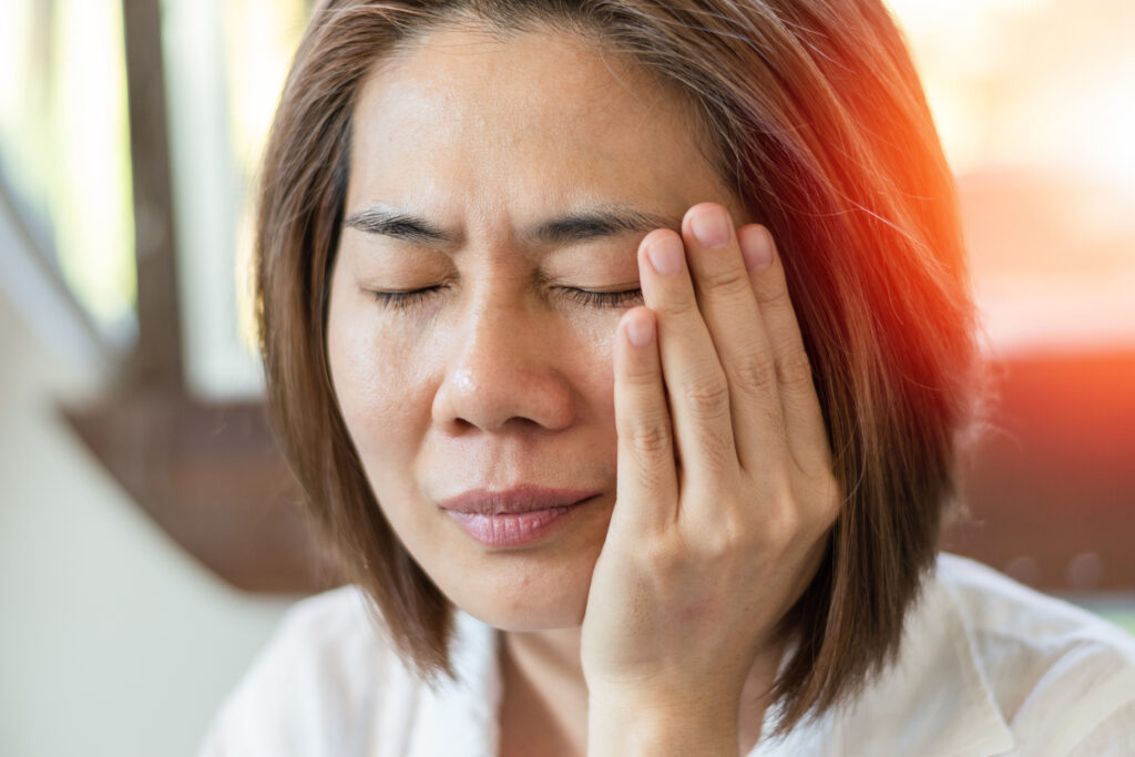 Asian woman holds hand on cheek face as suffering from facial pain, mumps or toothache